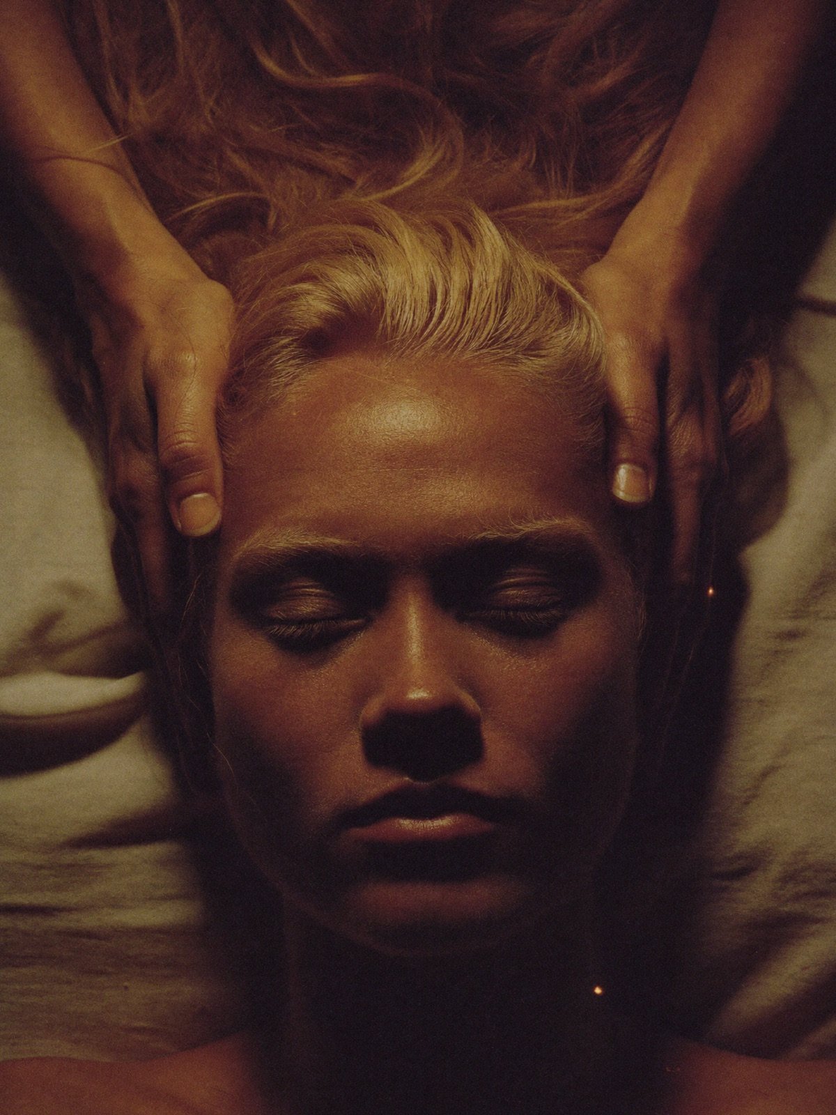 Hands gently cradling a guest's head from above during a scalp ritual